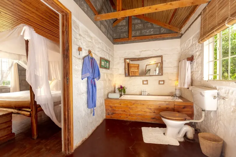 An en-suite bathroom with a timber-sided bath, a robe hanging ready