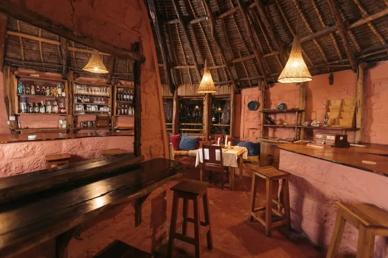 The bar under the thatch, shelves of bottles behind a long wooden counter