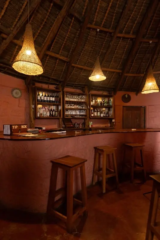 Wooden bar stools lined up beneath woven pendant lamps at the bar
