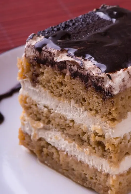 A slice of layered cake with a dark chocolate top