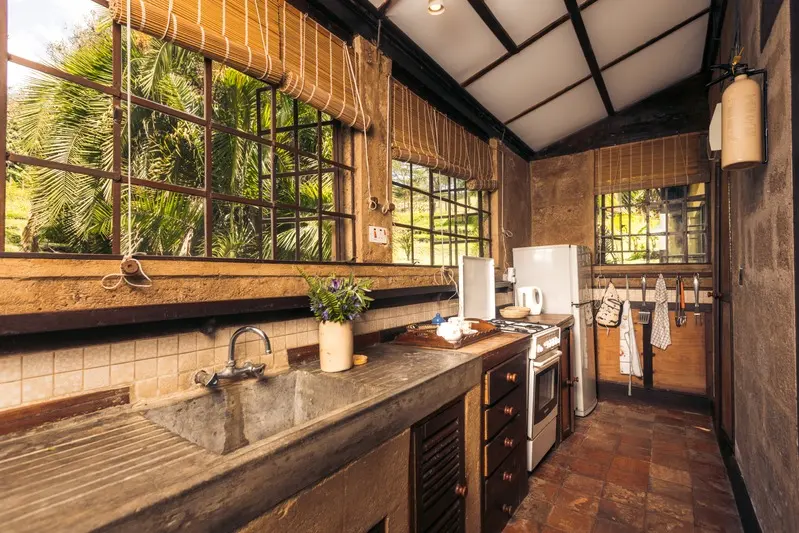 A rustic kitchen with a stone sink, timber counters and a gas cooker under the window
