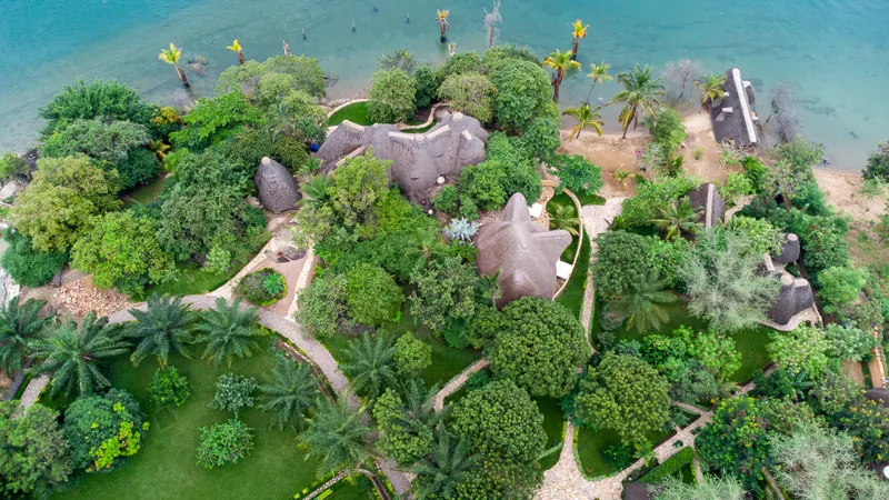 Aerial view of thatched villas in gardens along the shore of Lake Tanganyika