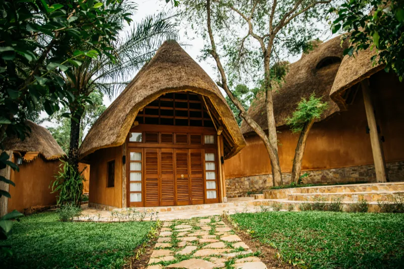 Thatched ochre buildings with louvred doors along a flagstone path
