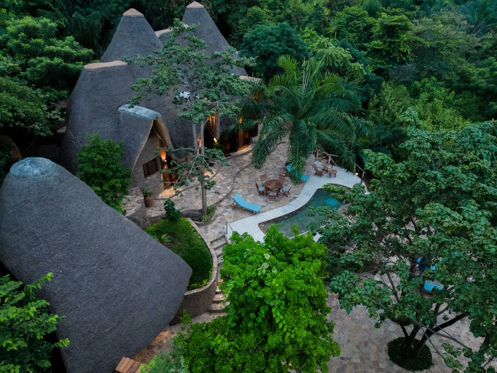 Aerial view of the thatched Turquoise villa with its curved private pool and terrace surrounded by dense forest